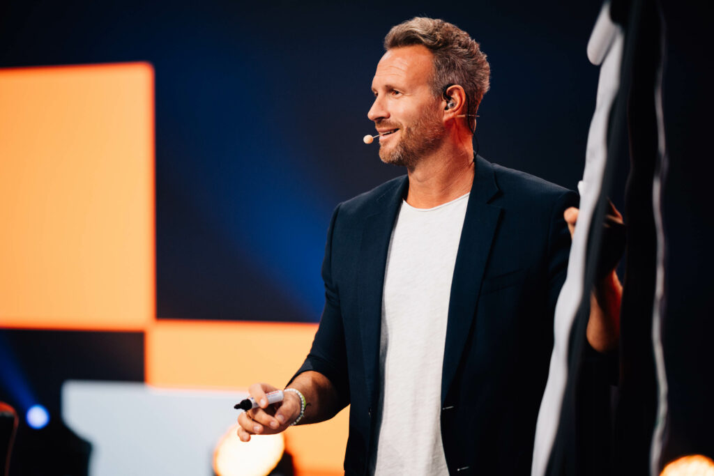 Pascal Feyh auf der Bühne mit einem Flipchart und Stift in der Hand