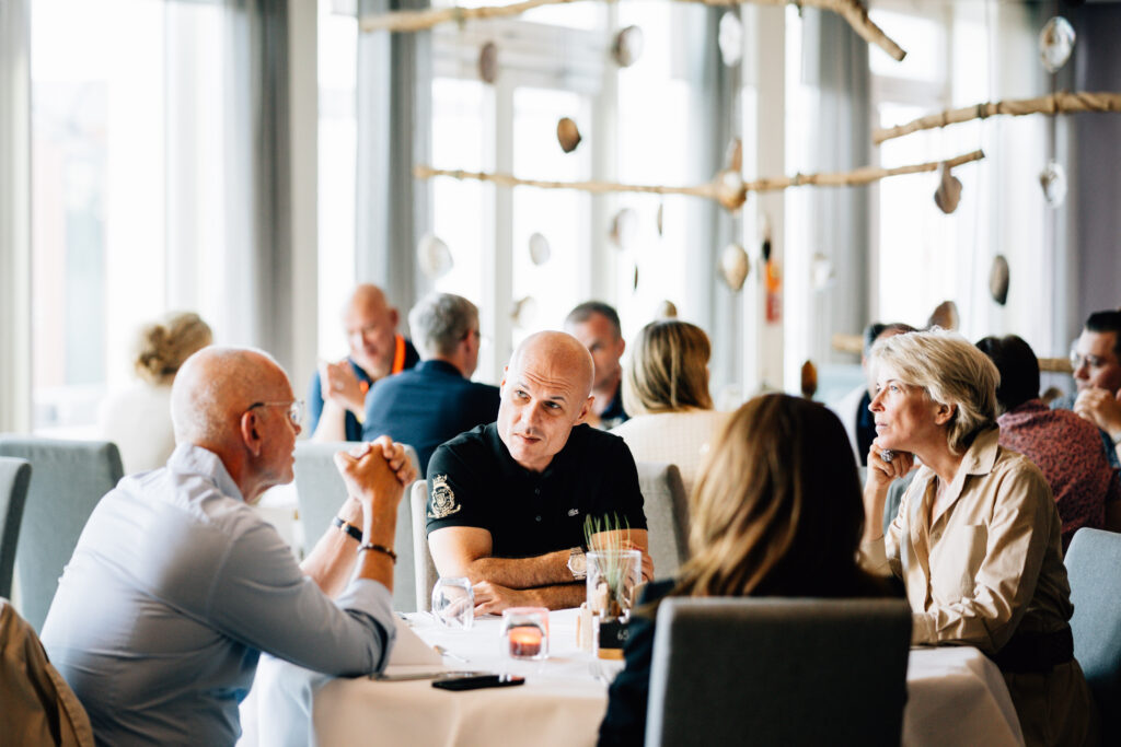 Nermin Fajic und Mike Dierssen sitzen mit Kunden am Tisch und sprechen