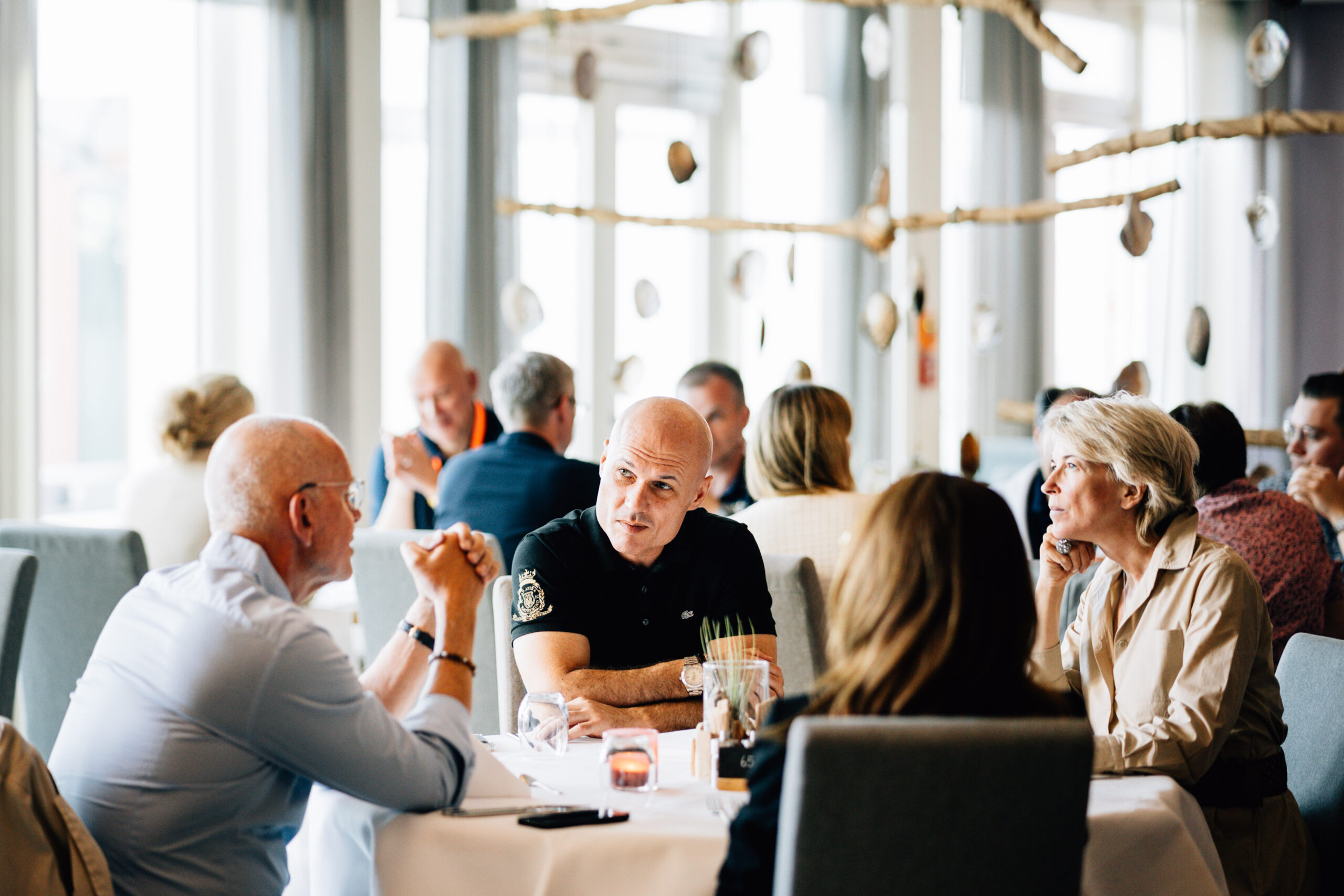 Nermin Fajic und Mike Dierssen sitzen mit Kunden am Tisch und sprechen